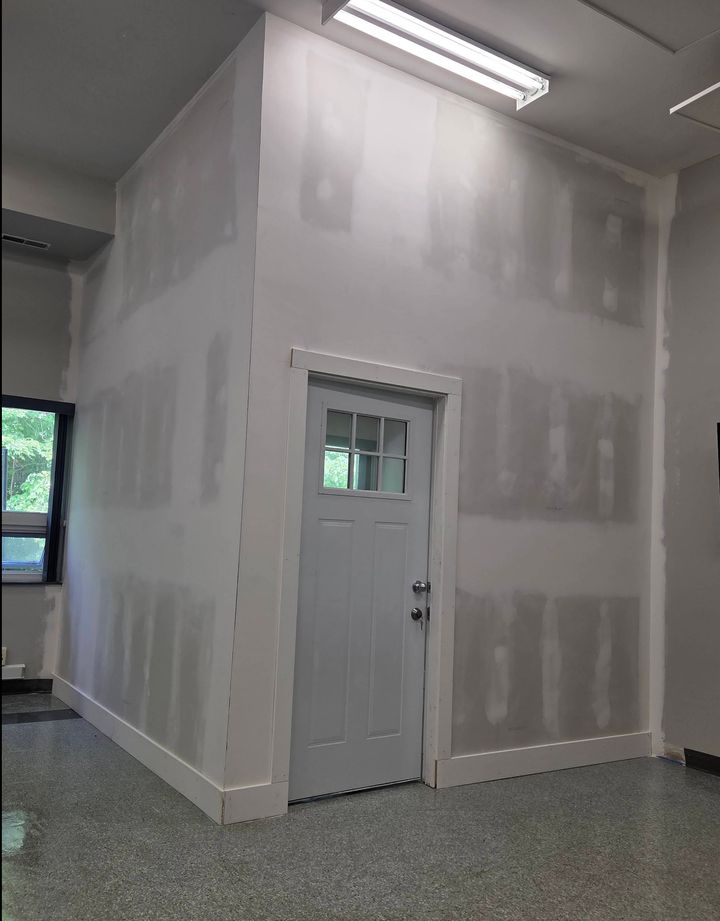 The same wall after drywall, taping and trim, with a new white door installed